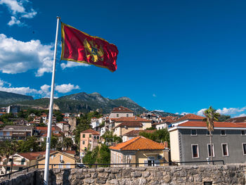 Flag by houses against blue sky