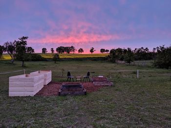 Empty bench on field against sky during sunset