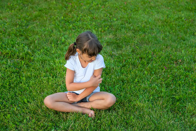 Side view of boy sitting on grassy field