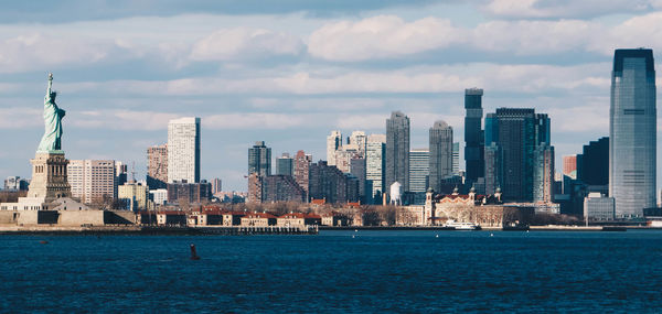 Sea by buildings against sky in city