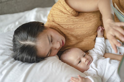 Mother sleeping with toddler on bed at home