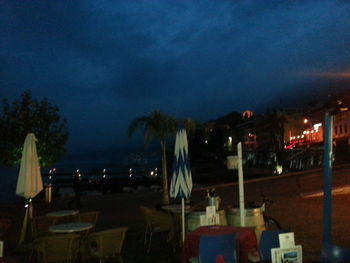 Chairs and tables against sky at night
