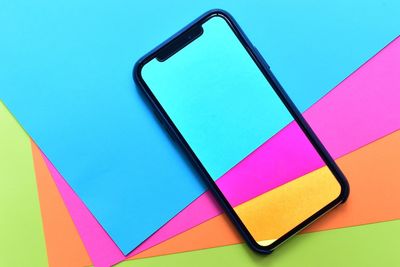 High angle view of phone cover on multi colored papers