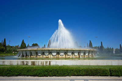 Fountain in park against blue sky