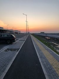 Road by street against sky during sunset