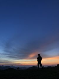 Silhouette man standing on field against sky during sunset