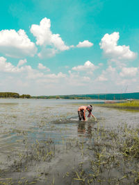 People on lake against sky