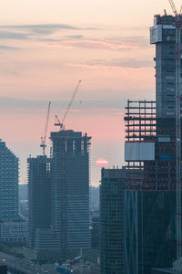 Buildings in city against sky during sunset