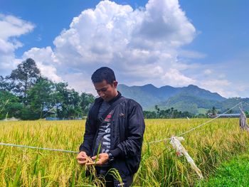 Young man standing on field against sky