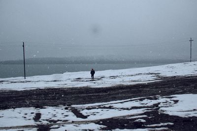 Rear view of man walking on snow covered landscape