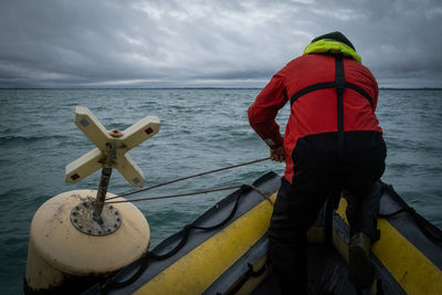 Rear view of man standing in boat in sea