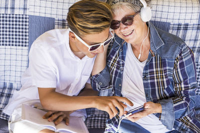 Grandmother with grandson reading book while sitting on sofa at home