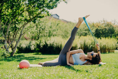 Woman exercising on mat with equipment in park