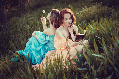 Young woman using phone while sitting on grass