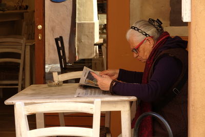 Side view of young woman sitting on table