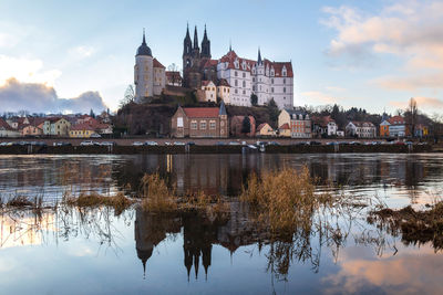 Reflection of church in lake against sky in city