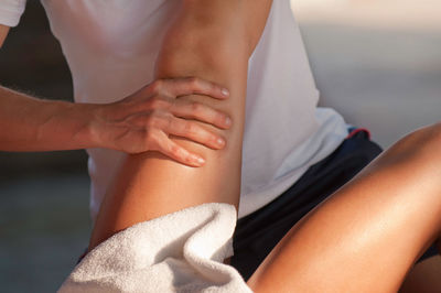 Midsection of masseuse giving massage on leg of woman