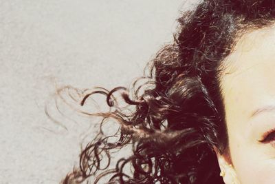 Cropped image of woman with curly hair against wall
