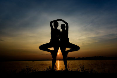 Silhouette man standing in sea against sky during sunset