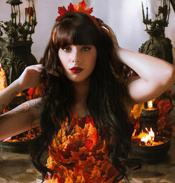 Portrait of young woman holding illuminated string lights