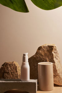 White ceramic opaque bottle on a beige background without labels on natural podium, stones 