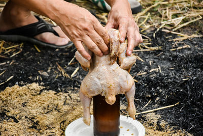 Cropped hands of man holding raw chicken meat outdoors