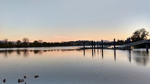 Scenic view of lake against clear sky at sunset