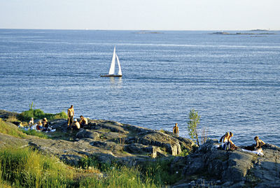 People on sailboat by sea against sky