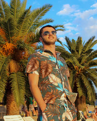 Low angle view of young man looking away against trees