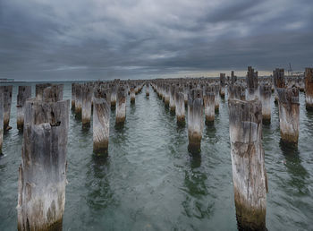 Panoramic view of wooden posts in sea against sky