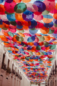 Low angle view of multi colored umbrellas hanging on building