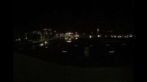 Illuminated cityscape by sea at night