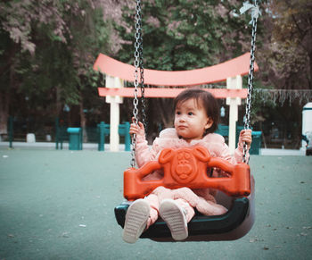 Cute boy sitting on swing at playground
