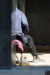 Low section of man sitting on street in city