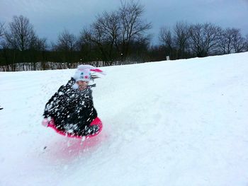 Child tobogganing on snow covered field