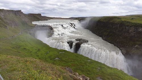 Scenic view of waterfall against sky