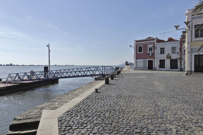 Footpath by sea against buildings in city