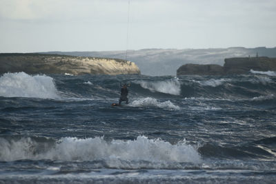 Man surfing in sea against sky