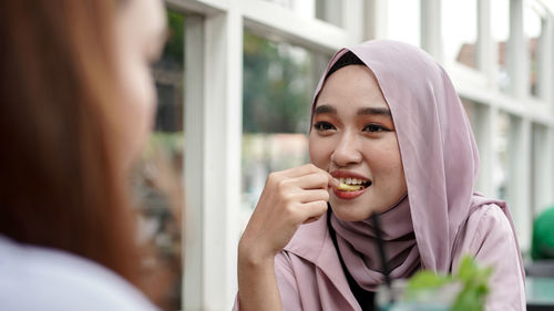 Close-up of woman eating food with friend in cafe