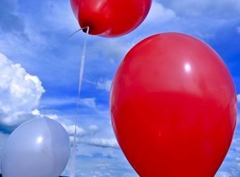 Low angle view of red balloons against sky