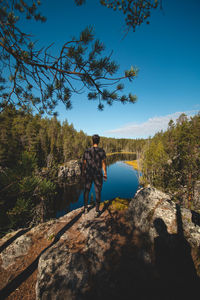 Traveller stands on high rock and observing  natural lake in hiidenportti park, sotkamo, finland. 
