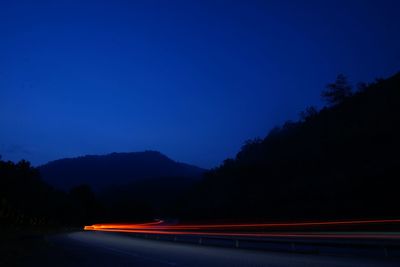 Light trails on road against sky at night