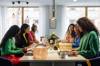 Multiracial female entrepreneurs working together while sitting at desk in office