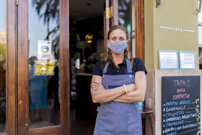 Confident female cafe owner wearing protective face mask during covid-19 outbreak