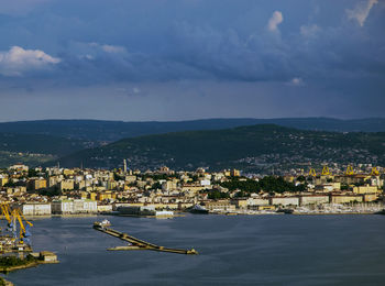 Aerial view of city by sea against sky