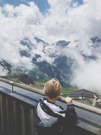 Rear view of boy standing by railing looking at view