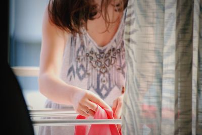 Midsection of woman putting laundry on rack