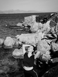 Portrait of man standing on rock by sea