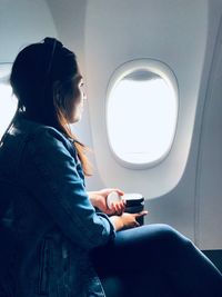 Side view of woman sitting in airplane