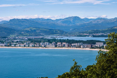 Scenic view of sea by townscape against sky